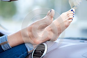 Close up of woman driver feet resting on car dashboard