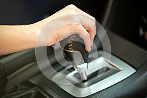 Close up of woman driver holding her hand on automatic gear shift stick driving as car