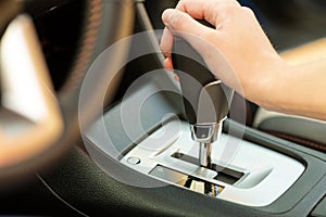 Close up of woman driver holding her hand on automatic gear shift stick driving as car photo