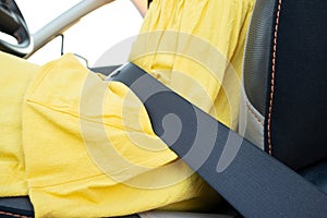 Close up of woman driver in yellow summer dress wearing seatbelt driving a car