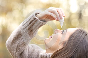 Woman with dry eyes applying artificial tear in winter photo