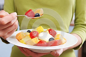 Close Up Of Woman Eating Bowl Of Fresh Fruit