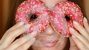 Close up woman eating a pink donuts.