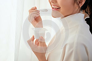 Close up woman eating yogurt behind the window