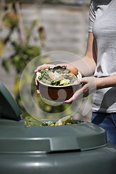 Close Up Of Woman Emptying Food Waste Into Garden Composter At Home