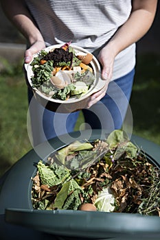 Close Up Of Woman Emptying Food Waste Into Garden Composter At Home