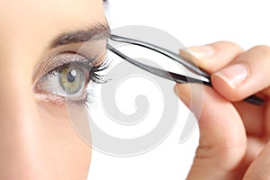 Close up of a woman eye and a hand plucking eyebrows photo