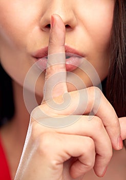 Close up of woman face holding finger on her lips