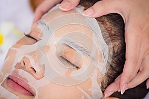 Close up woman face with mask in spa salon care. Young Asian girl relaxing with spa therapy. Beauty health lifestyle concept