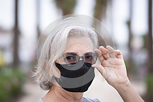 Close-up on woman face wearing a black face mask due to coronavirus - senior people and retirement concept