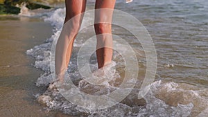 Close up woman feet walking barefoot on beach at sunset leaving footprints in sand female tourist on summer vacation.