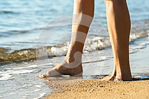 Close up of woman feet walking barefoot on sand leaving footprints on golden beach. Vacation, travel and freedom concept. People