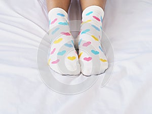 Woman feet wearing white sock with pastel heart shape pattern