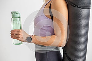 Close-up of woman with fitness gear and smartwatch. Sport concept. Reusable water bottle