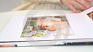 Close up. woman flips through photo book from family pregnancy photo shoot.