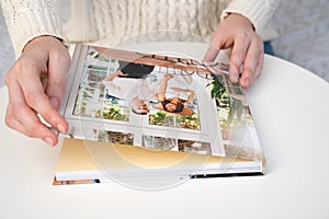 Close up. woman flips through photo book from family pregnancy photo shoot