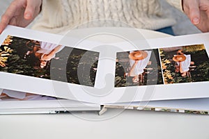 Close up. woman flips through photo book from family pregnancy photo shoot