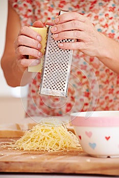Close Up Of Woman Grating Cheese In Kitchen photo