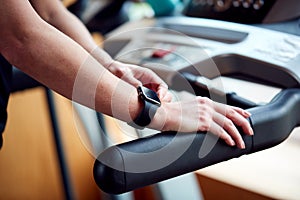 Close Up Of Woman In Gym Using Fitness App On Smart Watch On Running Machine