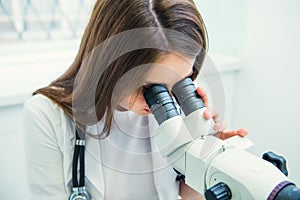 Close up woman gynecologist working with colposcope and makes microscopic investigation in clinic. Selective focus, copy space