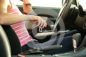 Close up of woman hand fastening seat belt while sitting inside a car for safety before driving on the road. Female driver driving