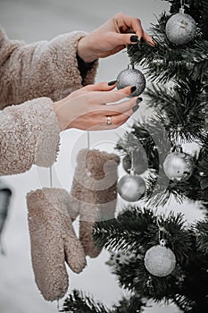 Close up of woman hand, hangs decoration ball on branch of Christmas tree
