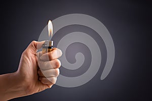 Close up woman hand holding a burning lighter in the dark background