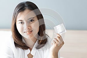 Close up woman hand holding condom lying on white bed, health care and medical concept