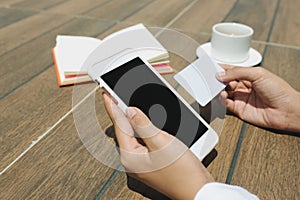 Close up woman hand holding credit card and blank screen mobile phone sitting at coffee shop