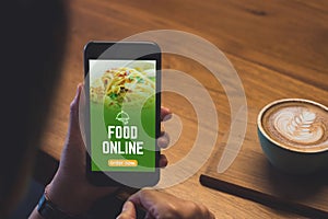 Close up woman hand holding food online mobile apps with hot coffee cup on table sitting at coffee shop,online order concept.