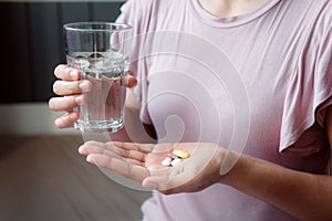 Close-Up Woman Hand is Holding Glass of Water While Taking Pills, Healthcare and Medicine Concept