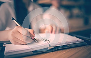 Close up of woman hand holding pen and writing on notebook