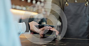 Close up of a woman hand holding a smartphone with an NFC payment technology used for paying for take away coffee in a