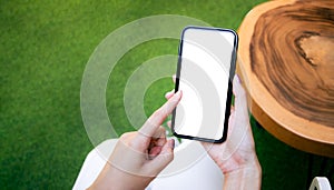 Close-up of woman hand holding a smartphone white screen is blank the background is blurred. obile phone Mockup