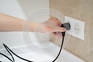 Close up Woman hand insert or pull out elecrticity plug in outlet on the wall