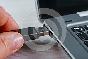 Close up of hand inserting USB flash drive into laptop computer on white background photo