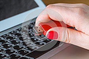 Close up of a woman hand plugging a pendrive on a laptop