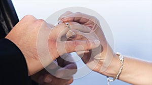 Close up of woman hand putting a wedding gold ring on the man finger. Action. Exchange rings for wedding registration of