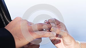 Close up of woman hand putting a wedding gold ring on the man finger. Action. Exchange rings for wedding registration of