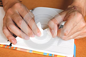 Close up woman hand ripping or tear white paper on notebook