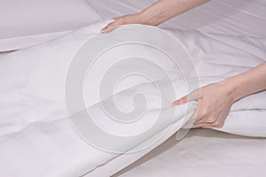 Close up woman hand set up white bed sheet in hotel room