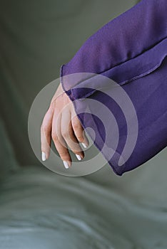 close up of woman hand in the studio with violet dress with delicate soft natural light. Concept of hand care and manicure.