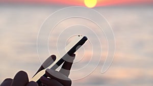 Close-up of a woman hand texting in a messenger or texting on a smartphone at an airport window. Silhouette of hands a