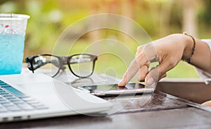 Close up woman hand use cell phone with laptop in coffee shop.