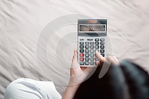 Close-Up of Woman Hand is Using Calculator for Calculated Accounting Money Saving or Expense Claim on Her Bedroom, Business photo