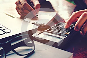 Close up woman hand using calculator and writing make note with