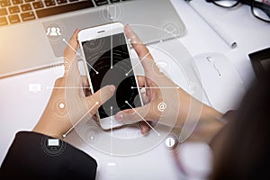 Close up of a woman hand using a white smart phone on a desk