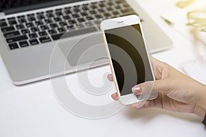 Close up of a woman hand using a white smart phone on a desk