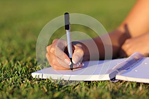Close up of a woman hand writing on a notebook outdoor