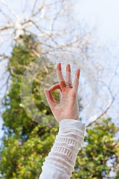 Close up woman hand   in yoga mudra gesture from below view to the sky and tree